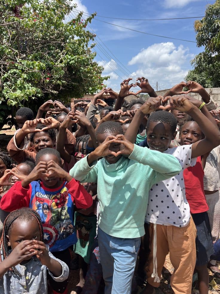 Children at a Ythirst outreach making heart shapes with their hands